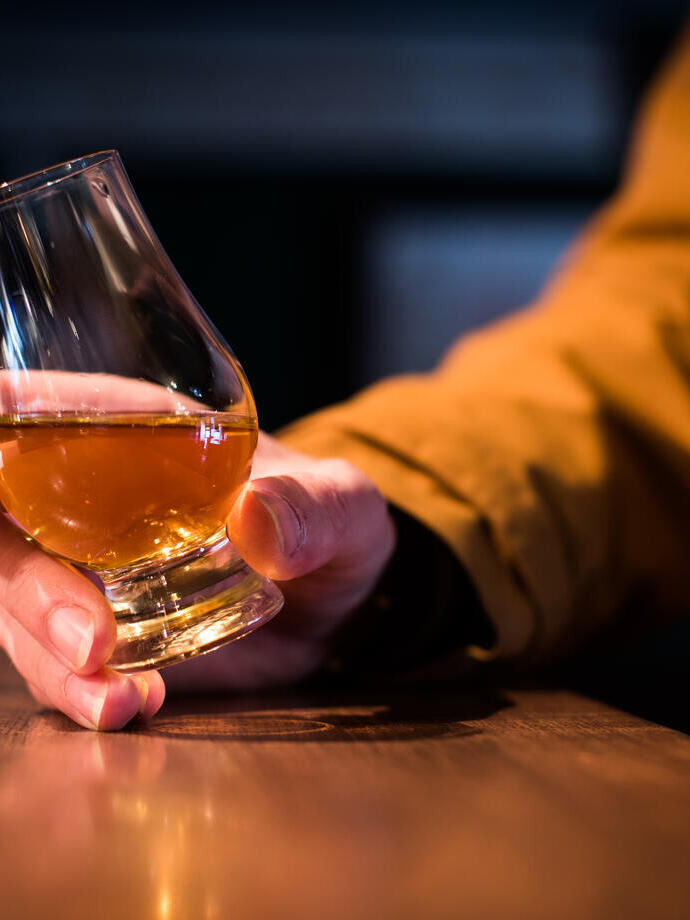 Close up shot of a hand holding a whisky glass
