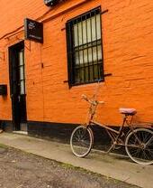 Bicycle parked outside jewellery boutique with orange painted wall in the Hidden Lane, Glasgow.
