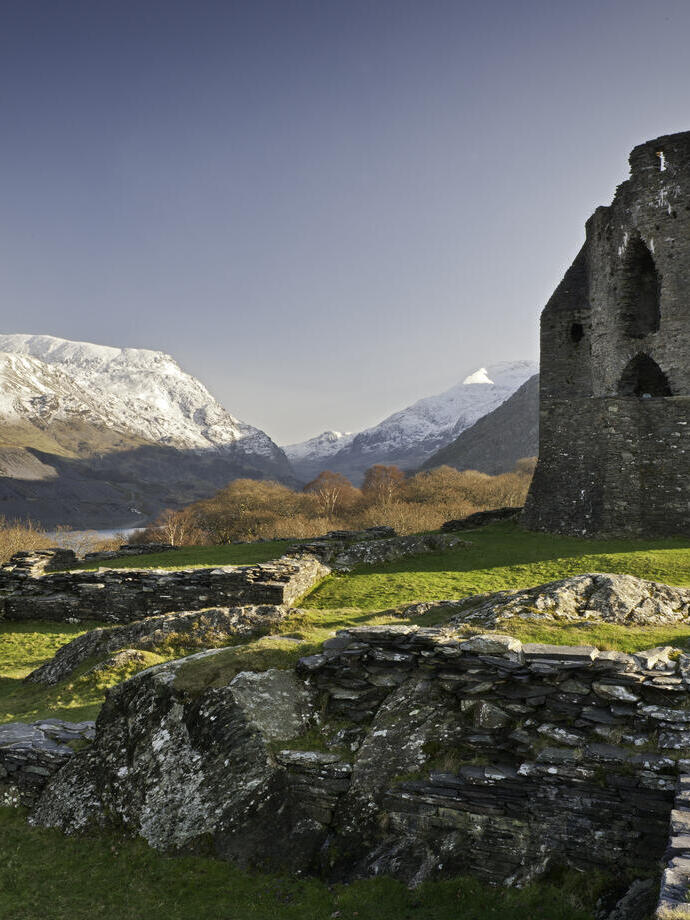 Ruines d'un château dans la campagne entourée de montagnes.