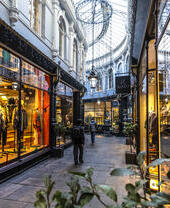 People walking between shops in an arcade, lit up from inside