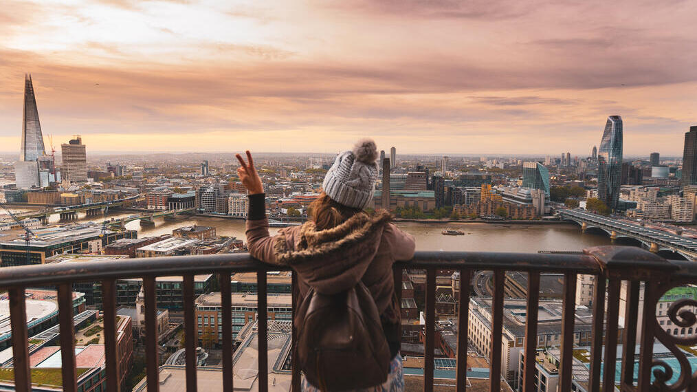Donna su un balcone in cima a un edificio alto che guarda la città