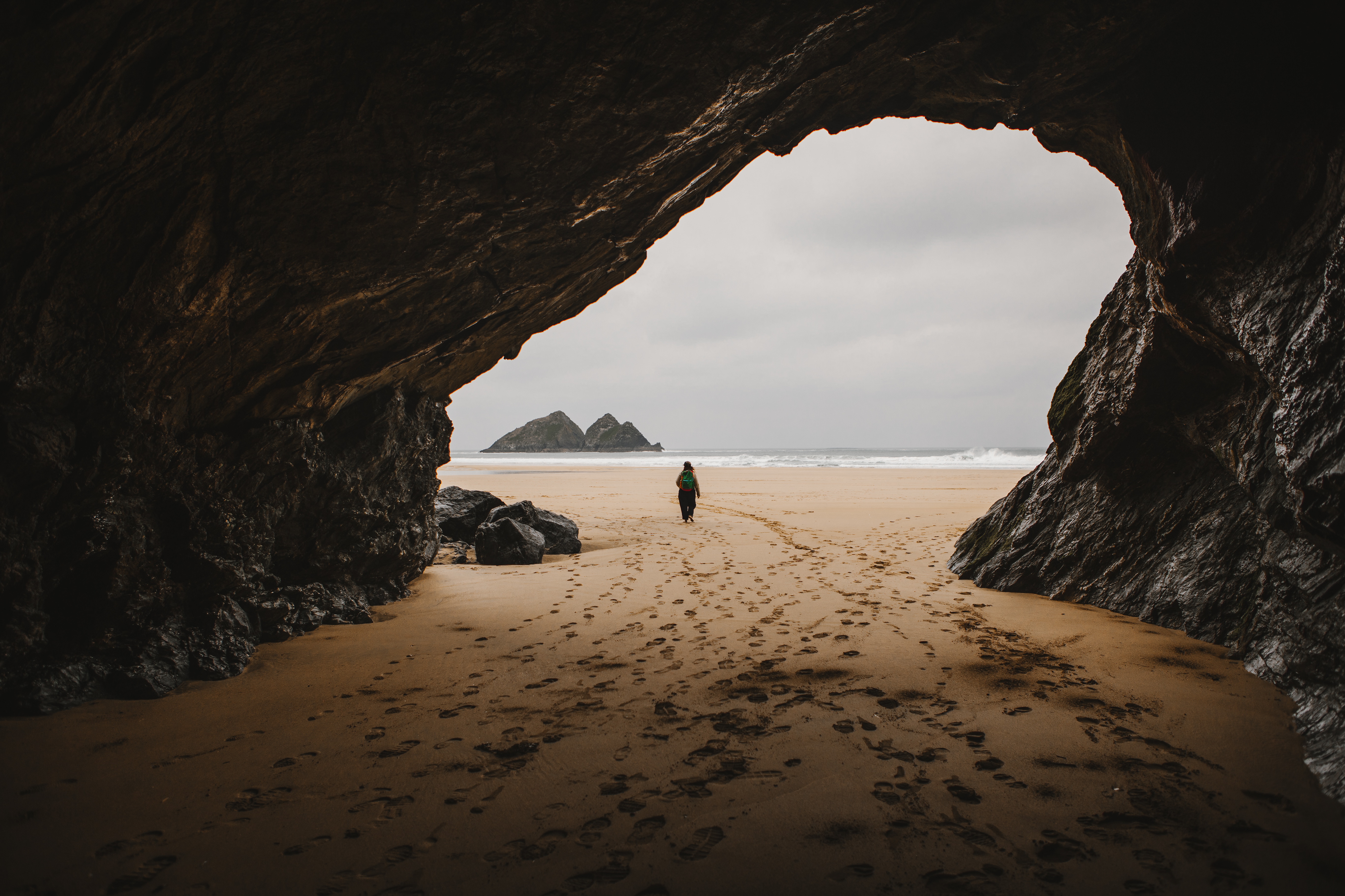 Une femme marche dans une grotte sur une plage