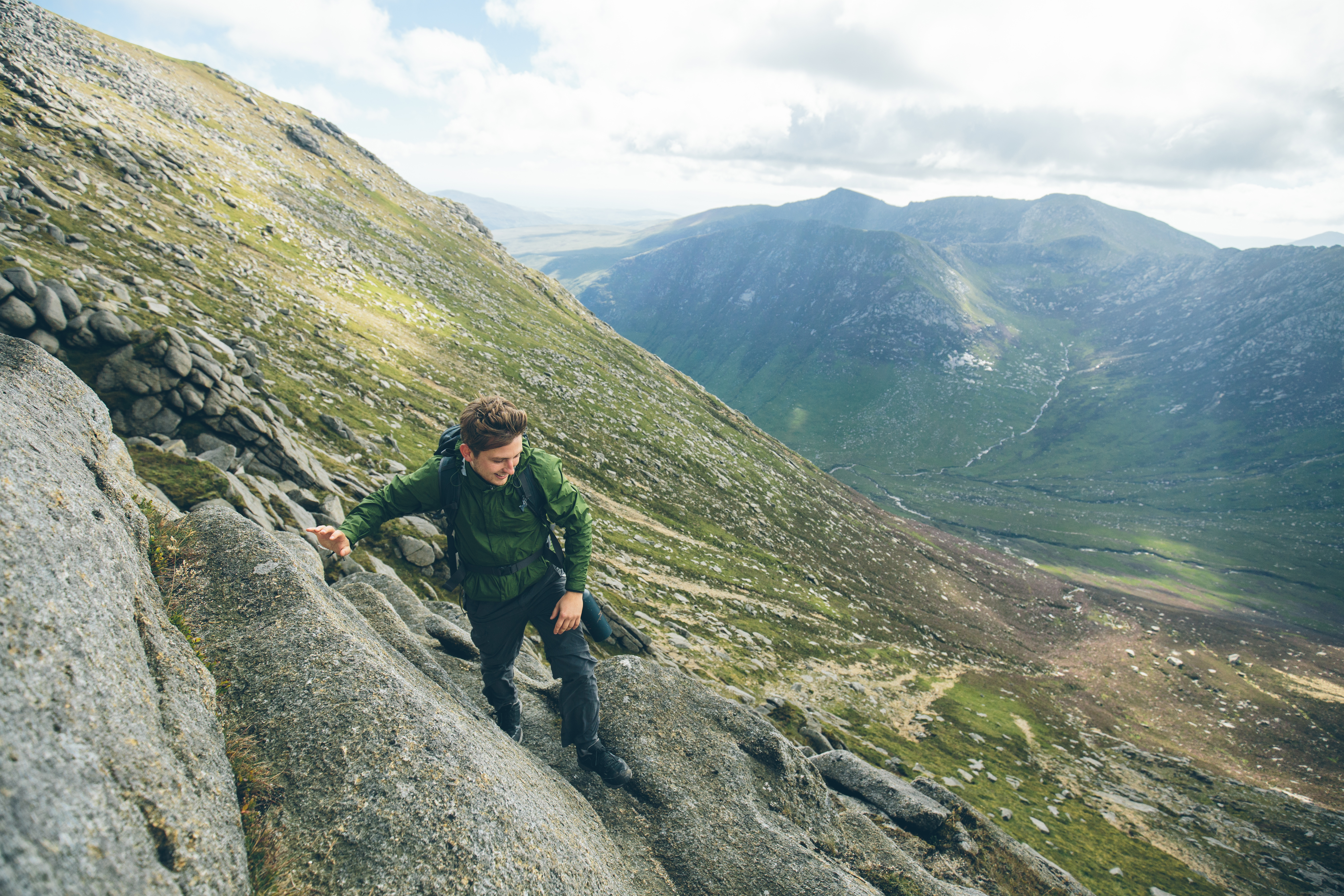 Hombre escalando la cima de una montaña escarpada.