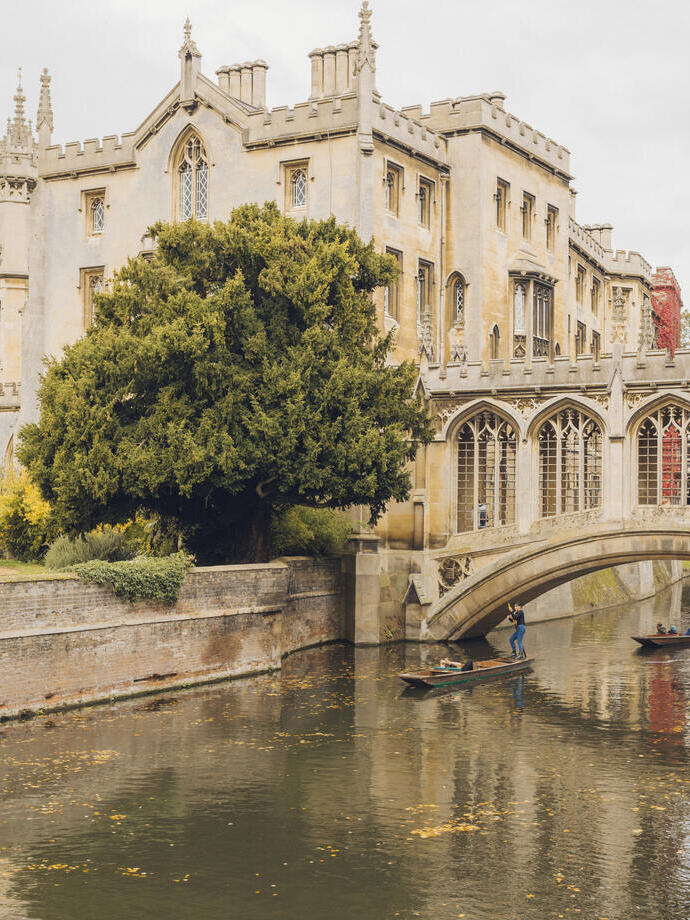 Gente navegando en barca por el río bajo un puente frente a un edificio histórico