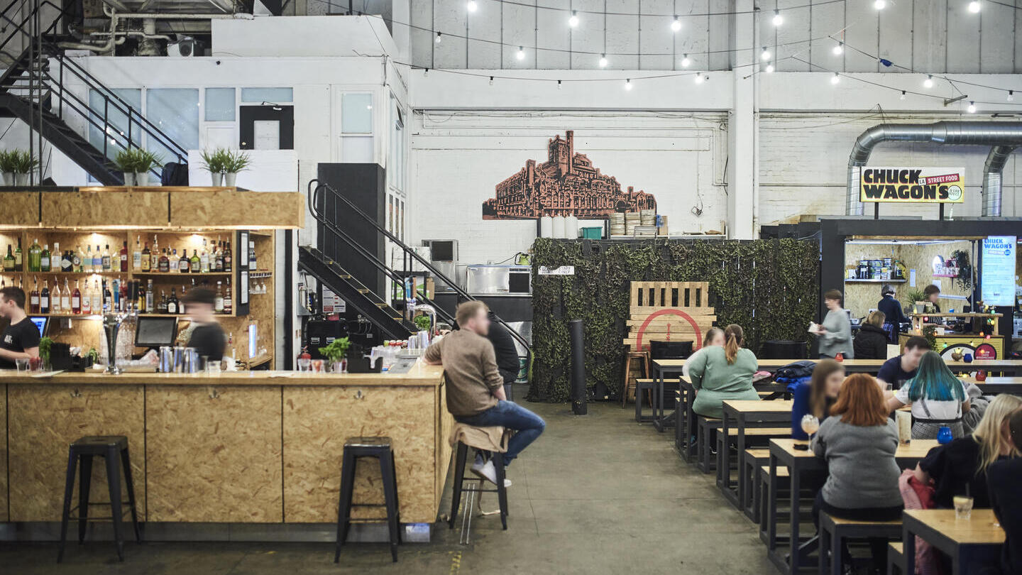 ساحة طعام داخلية بها أكشاك طعام خشبية ومقاعد للنزهات