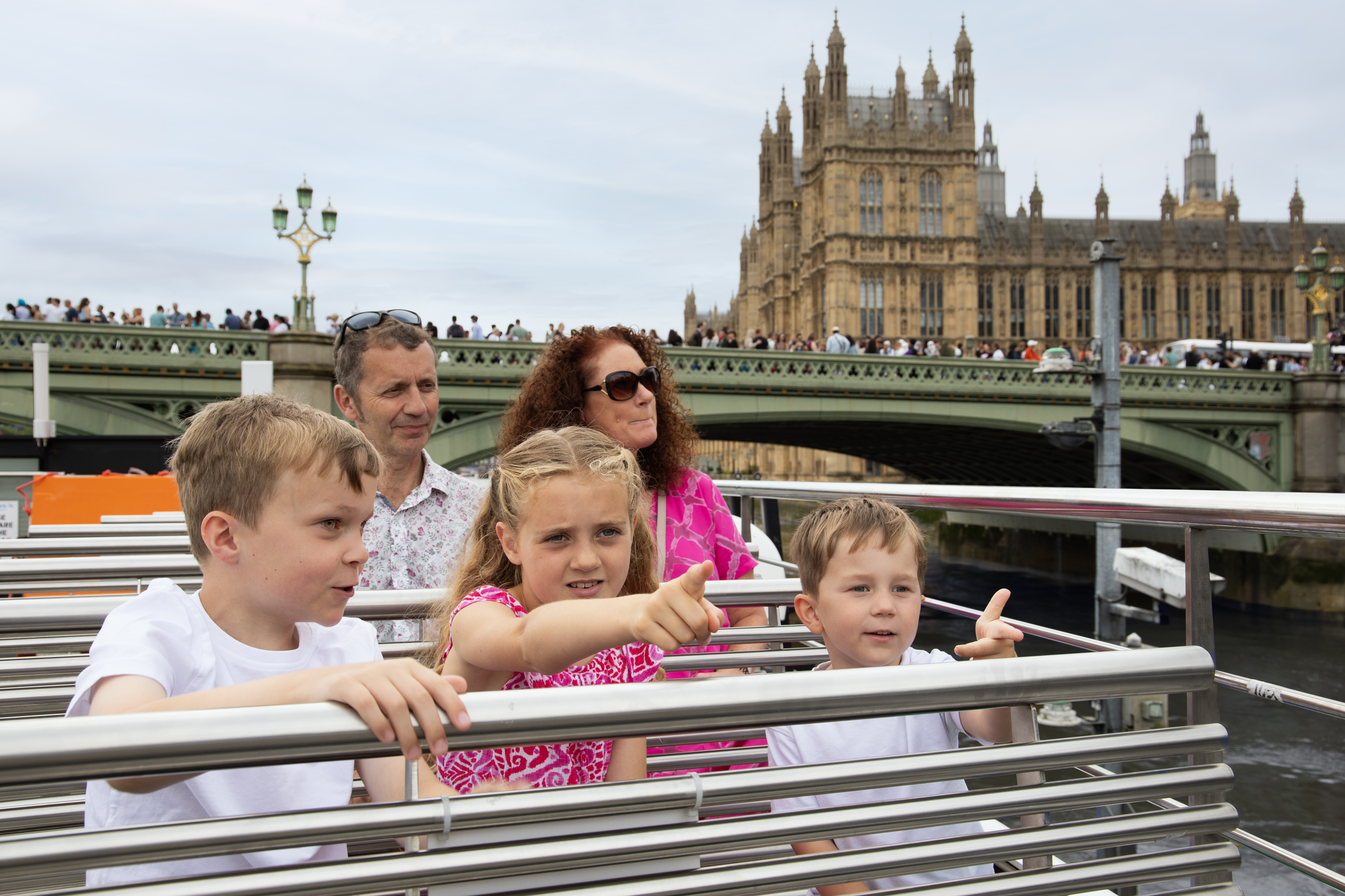 A family enjoying an open deck city cruise and sights in the background.