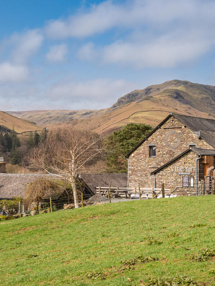 An external view across the field to some buildings, with the hills in the distance