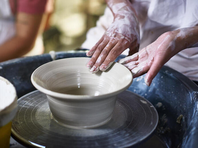Woman making pottery bowl on a pottery wheel.