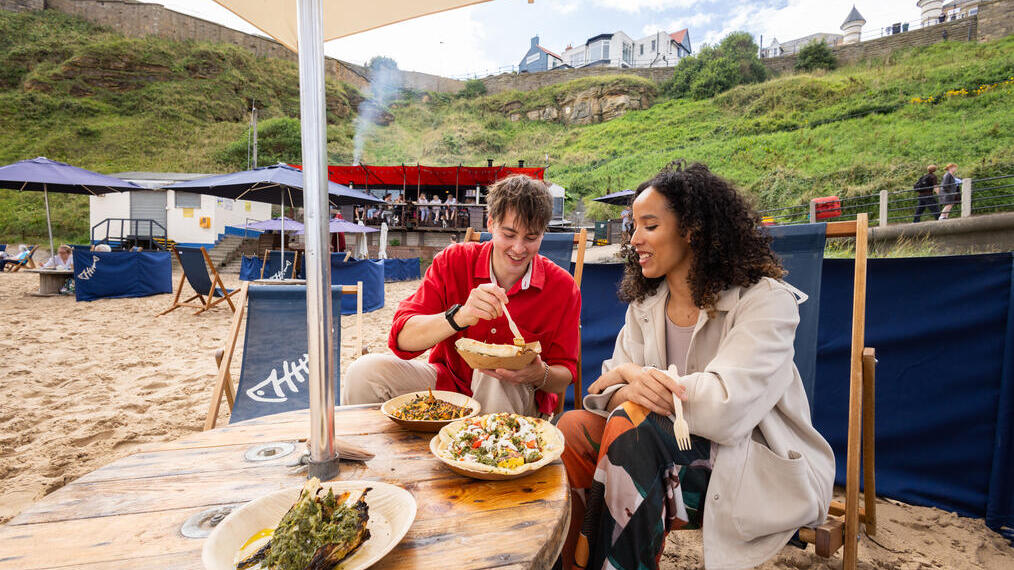 Coppia che mangia in un bar-ristorante sulla spiaggia con il mare sullo sfondo