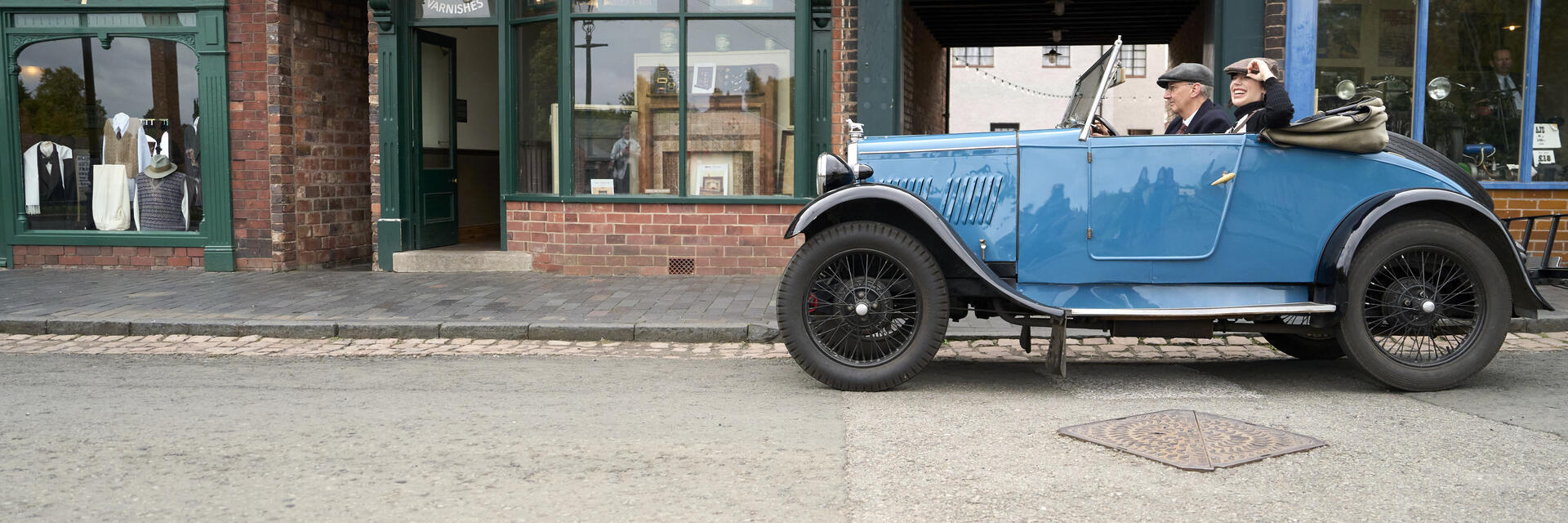 Two people inside a vintage car at a living museum