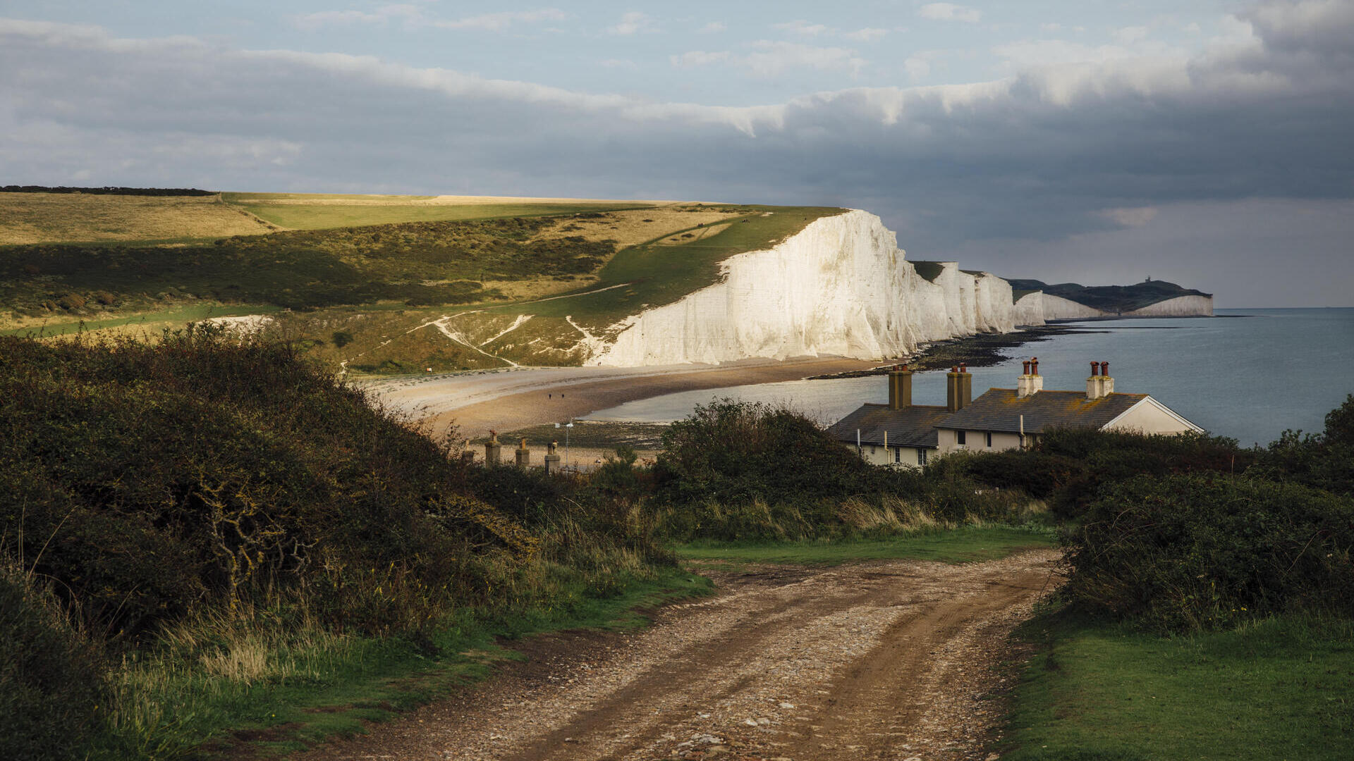 Ferienhäuser an der Küste mit Meer und weißen Klippen im Hintergrund