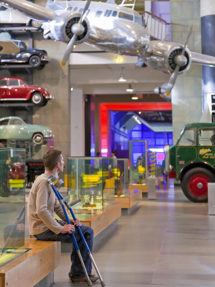 رجل جالس، ينظر إلى المعروضات في متحف وهو يحمل عكازاته