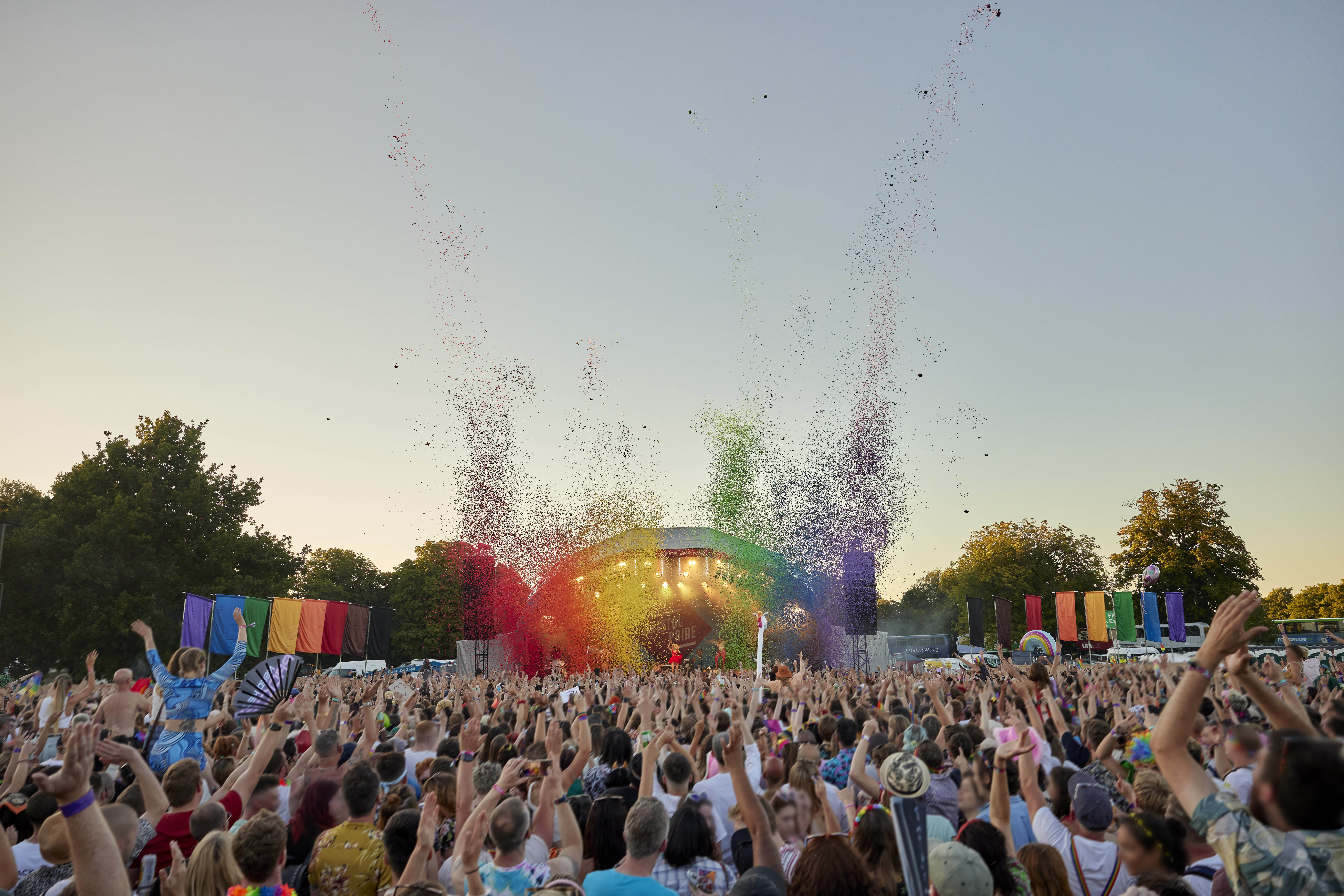 Rear view of crowd at event, stage decorated with rainbow colours