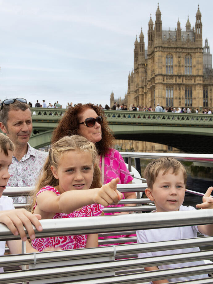 A family enjoying an open deck city cruise and sights in the background.