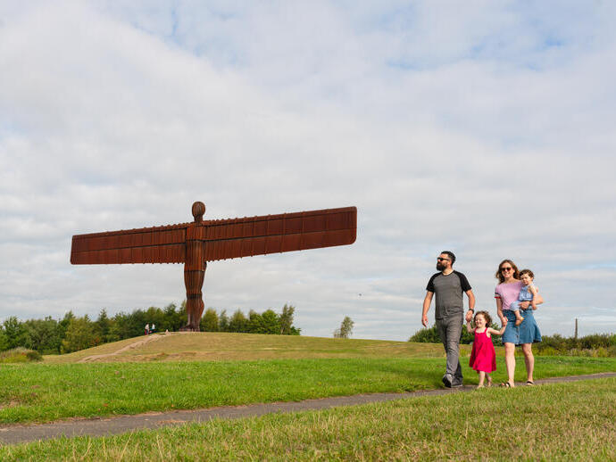 Eine Familie spaziert vor dem ikonischen Angel of the North, der sich südlich von Newcastle Gateshead befindet