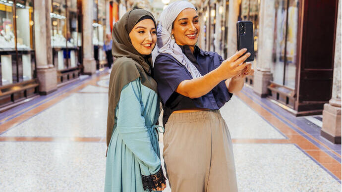 Two women take a picture together in an indoor shopping arcade