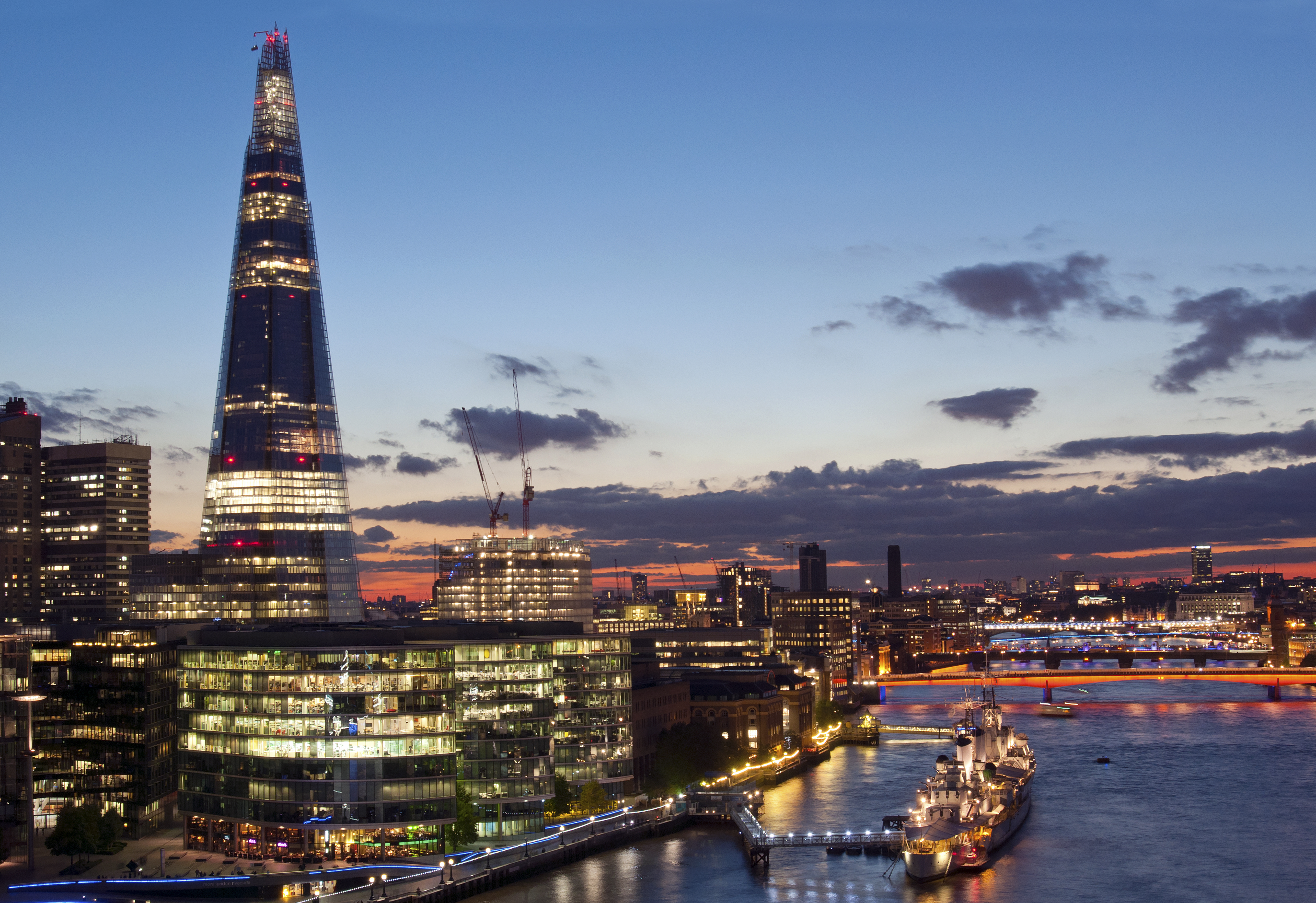 City buildings lit up at night on the banks of a river