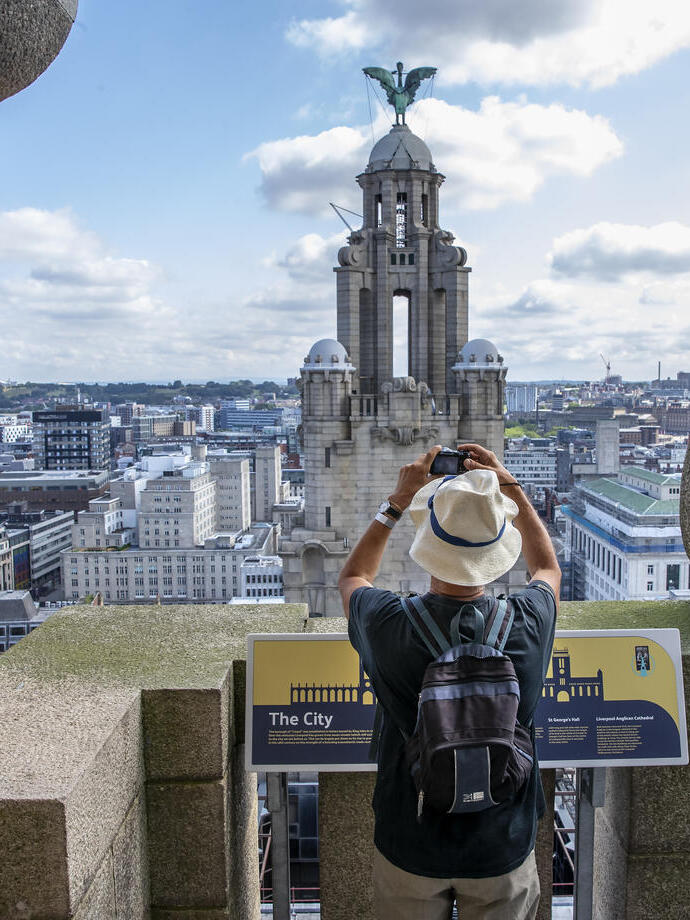 Gentleman photographing the tower in the skyline from the roof of the Royal Liver Building 360, Merseyside.