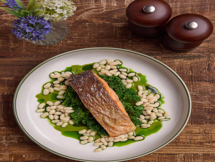 A fish dish at on a kale leaf and beans