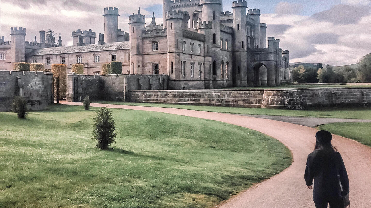 امرأة تسير على طريق يؤدي إلى قلعة