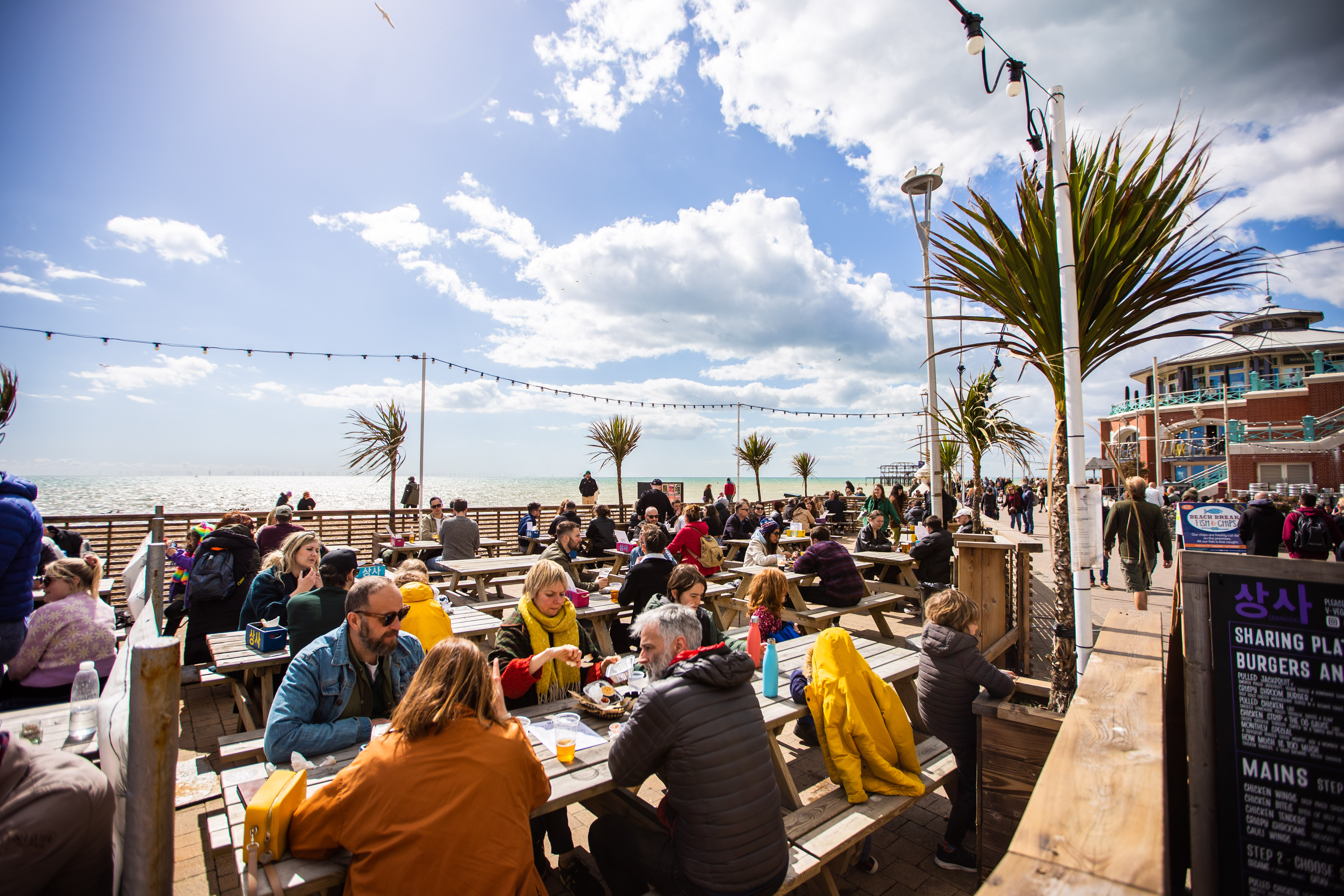 People eating outside by the beach in the sunshine