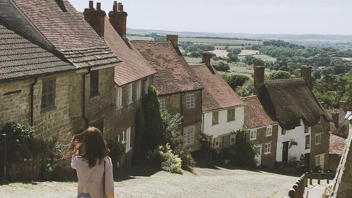 Donna che cammina lungo una ripida strada acciottolata di un villaggio in estate