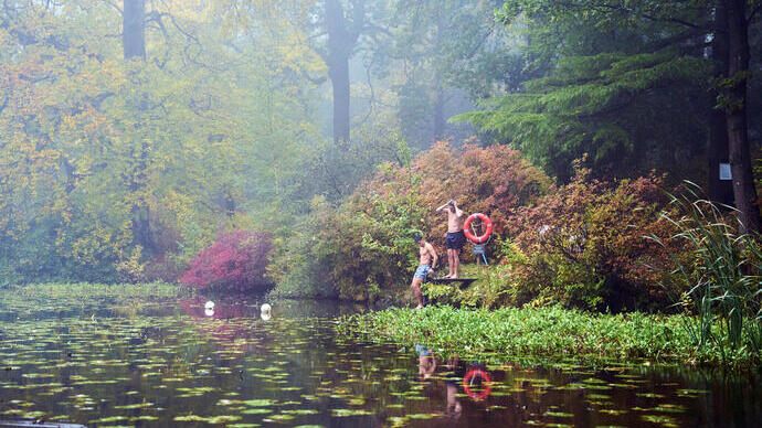 Two men on the swimming platform of a lake in an autumnal setting