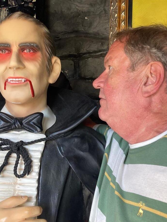 Man looking closely at wax model of Dracula, part of the Dracula Experience