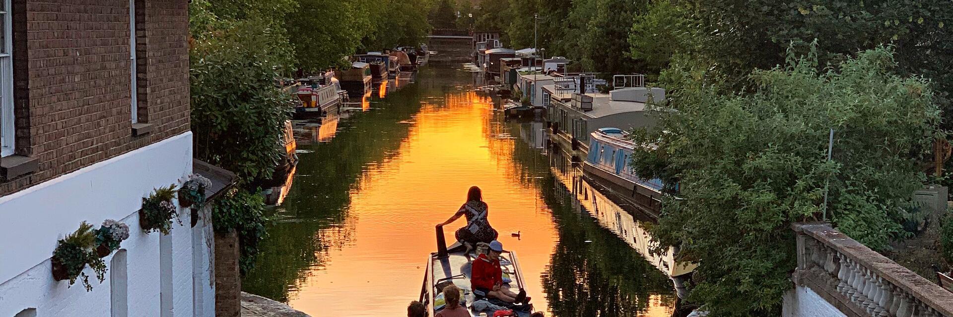 Menschen auf einem schmalen Boot auf einem Kanal bei Sonnenuntergang