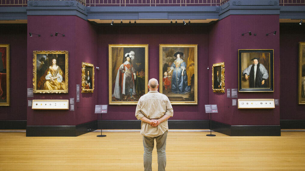 Rear view of man standing looking at portraits in a gallery