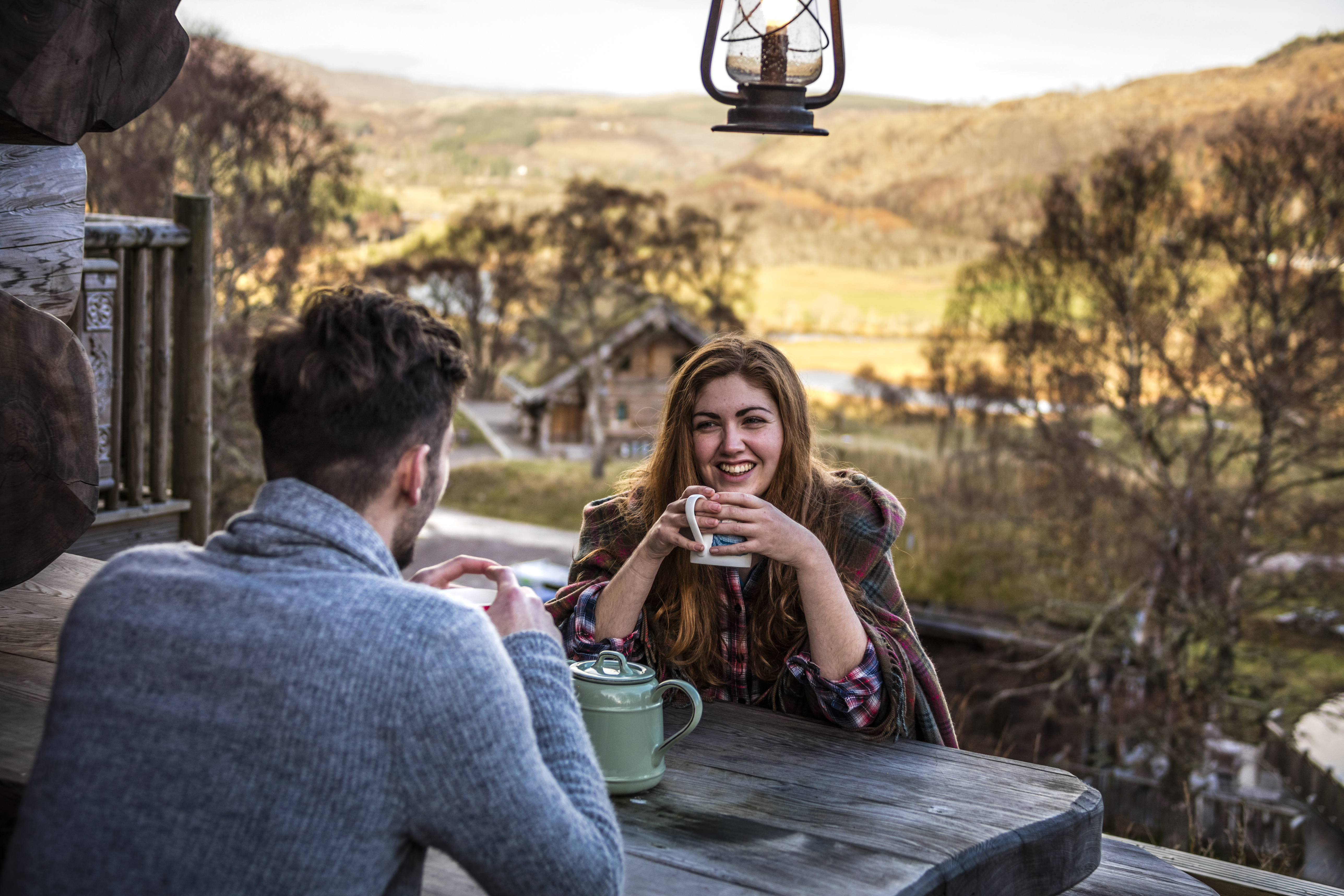 Couple sat at a wooden table drinking tea in a valley