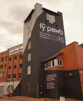 Vista esterna di un edificio con un'insegna che recita "Ty Pawb".