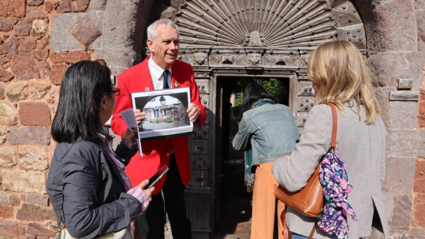 A tour guide in a red blazer leading a tour group around the centre of city