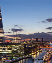 City buildings lit up at night on the banks of a river
