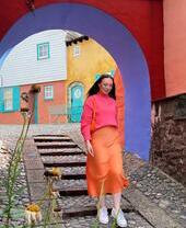 Woman walking on a cobbled street, under a colourful archway