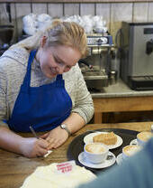 Une barista sourit en notant une commande dans son café local.