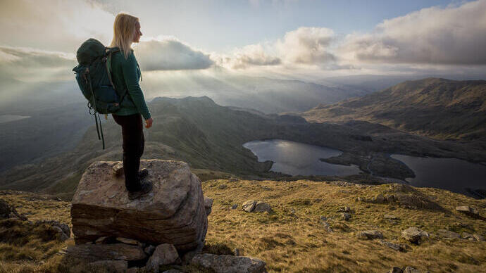 Una giovane donna in piedi sulle rocce in un punto panoramico.