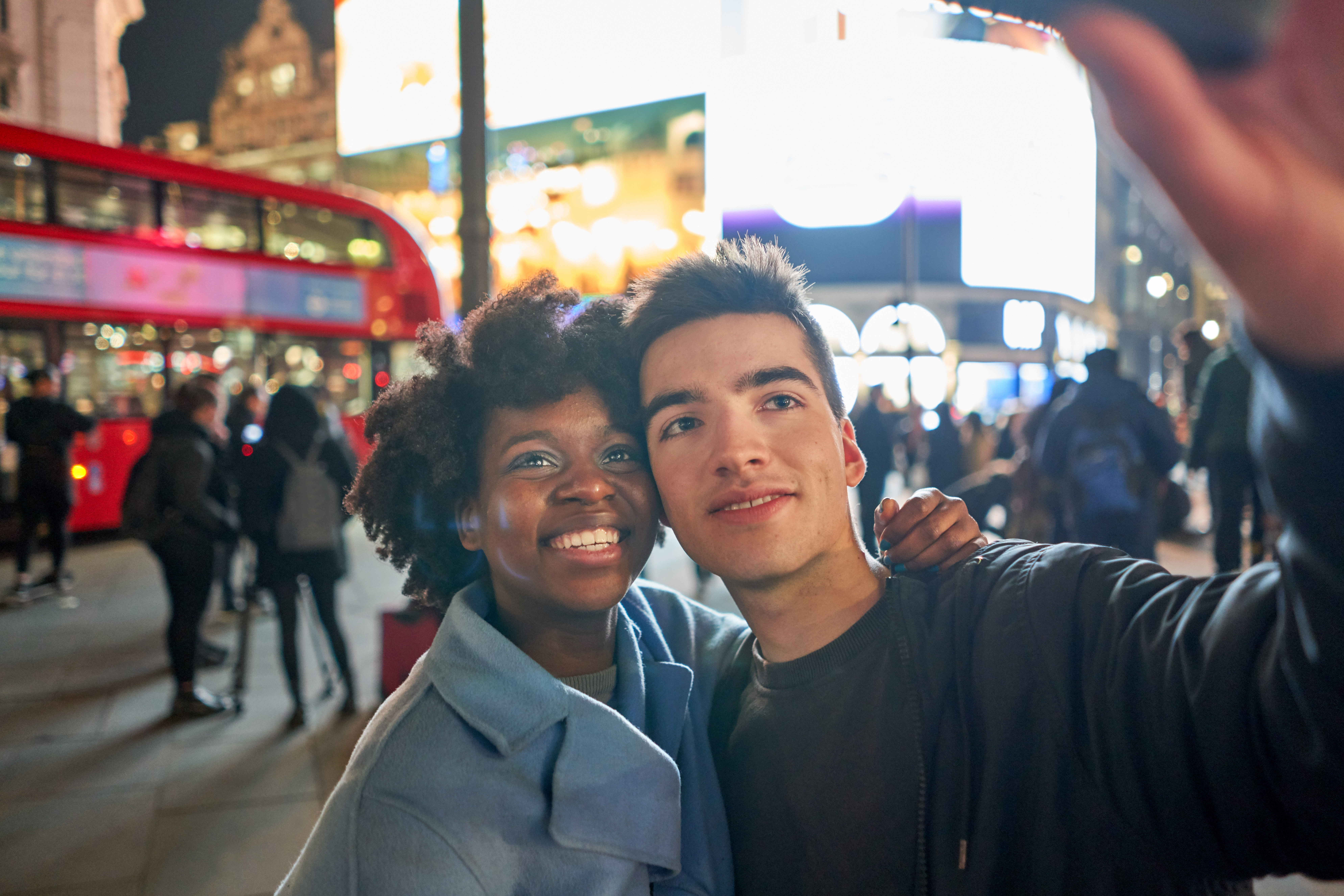 Couple taking a selfie on a phone in a busy city