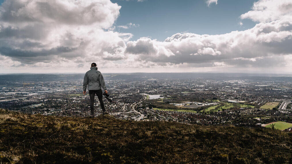 Un hombre de pie en la cima de una colina con vistas a la ciudad