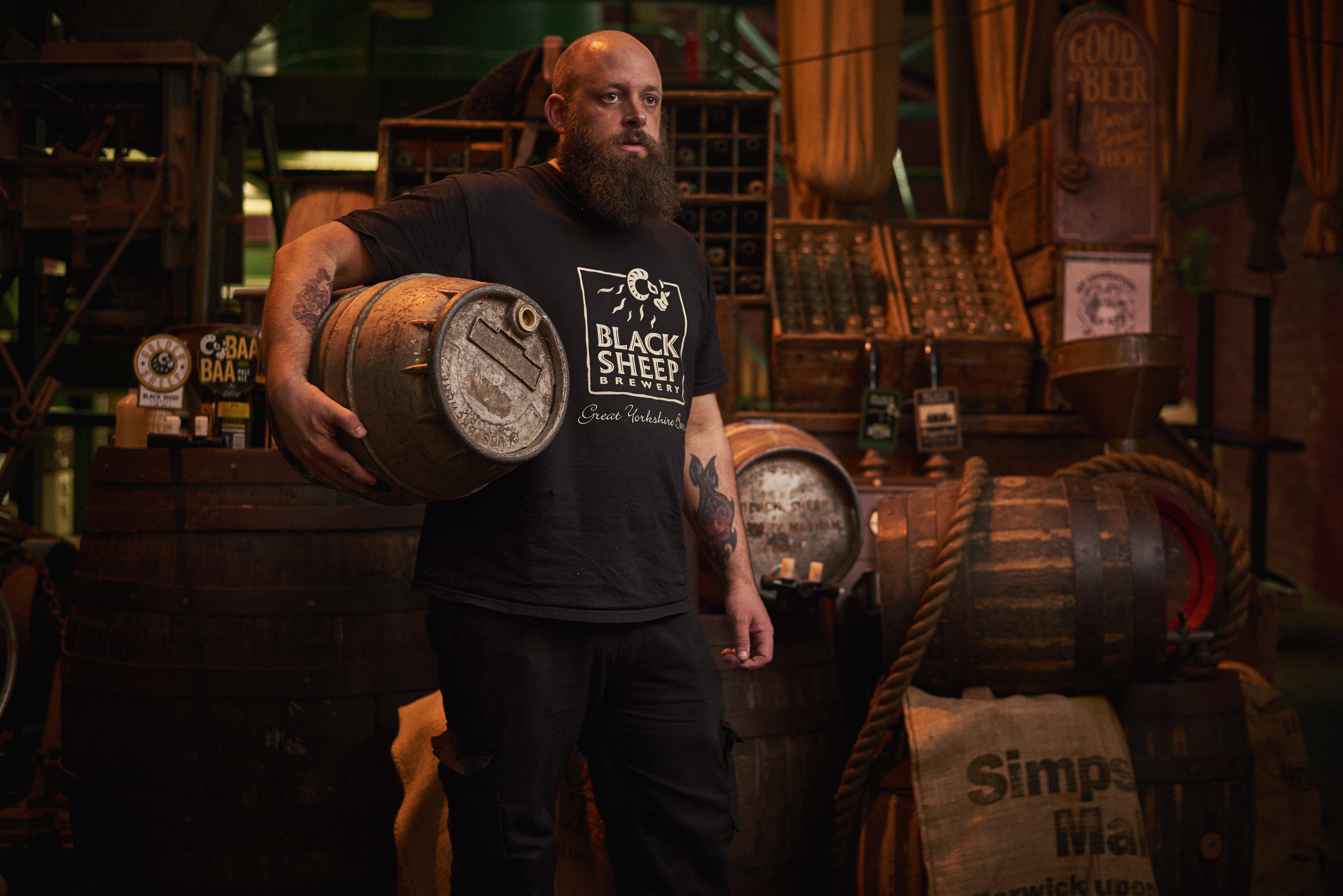 Man standing in store room, holding wooden beer barrel