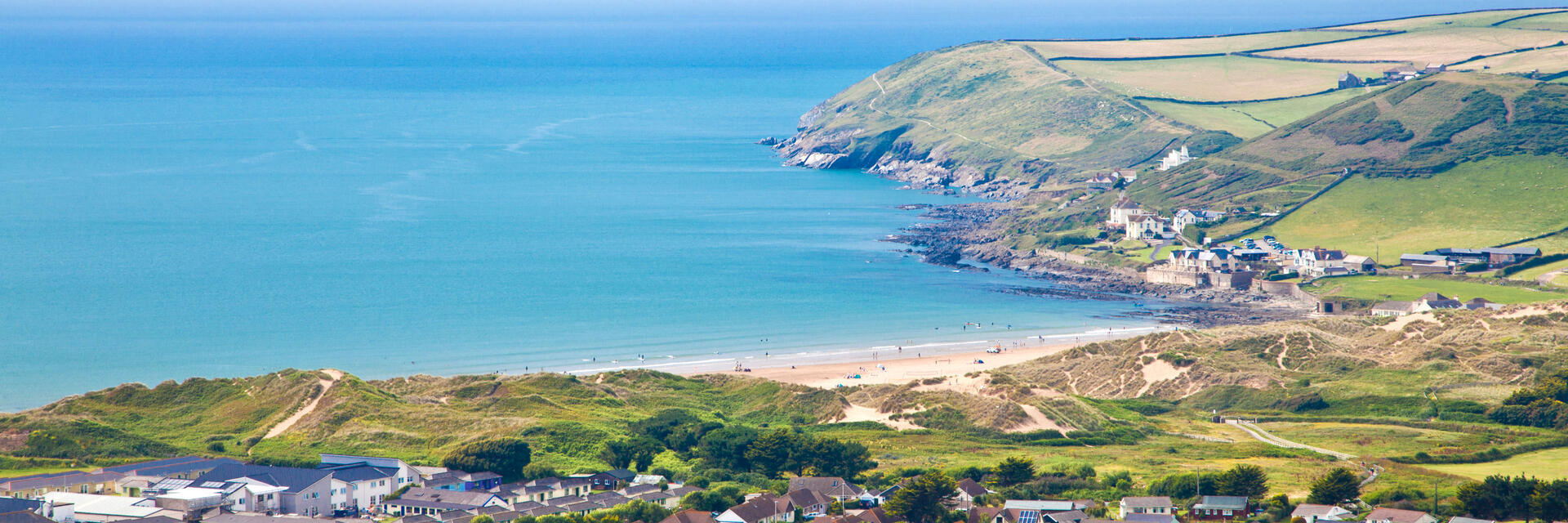 A clear view of a village from above and bay across mountains and out to the ocean