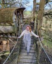 Jeune femme traversant un pont de corde depuis une cabane en bois dans un arbre