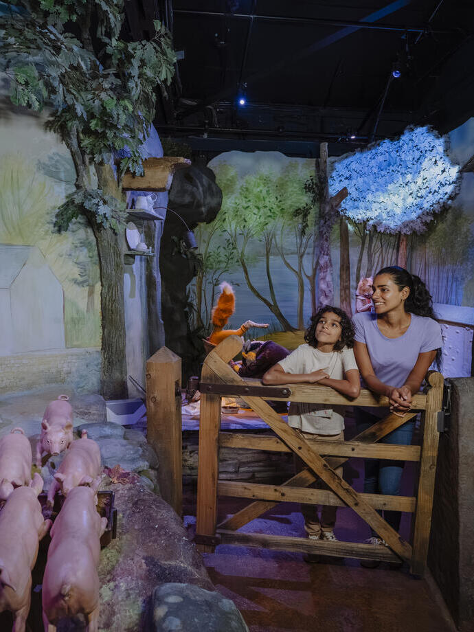 Scène intérieure avec des statues de cochons et des personnes qui les regardent dans un espace de divertissement.