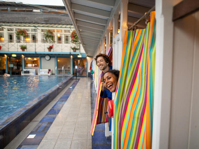 Man and woman peek out of changing rooms before going for a swim