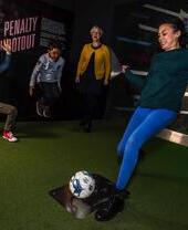 A group of people taking part in a penalty shootout exhibit in the National Football Museum in Manchester