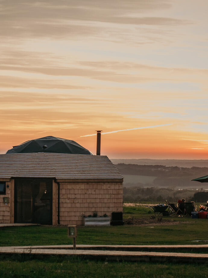 People having a BBQ next to a glamping dome at sunset