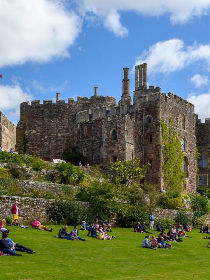 Crowds enjoying a sunny afternoon on the grounds of a castle.