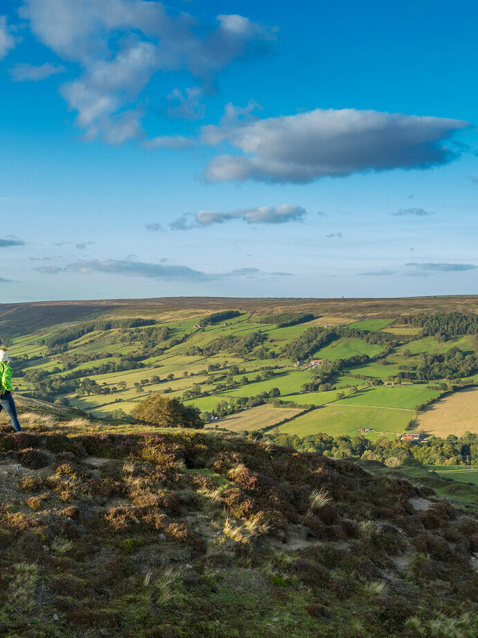 Eine Frau spaziert einen Pfad entlang auf einem Hügel und genießt die Aussicht.