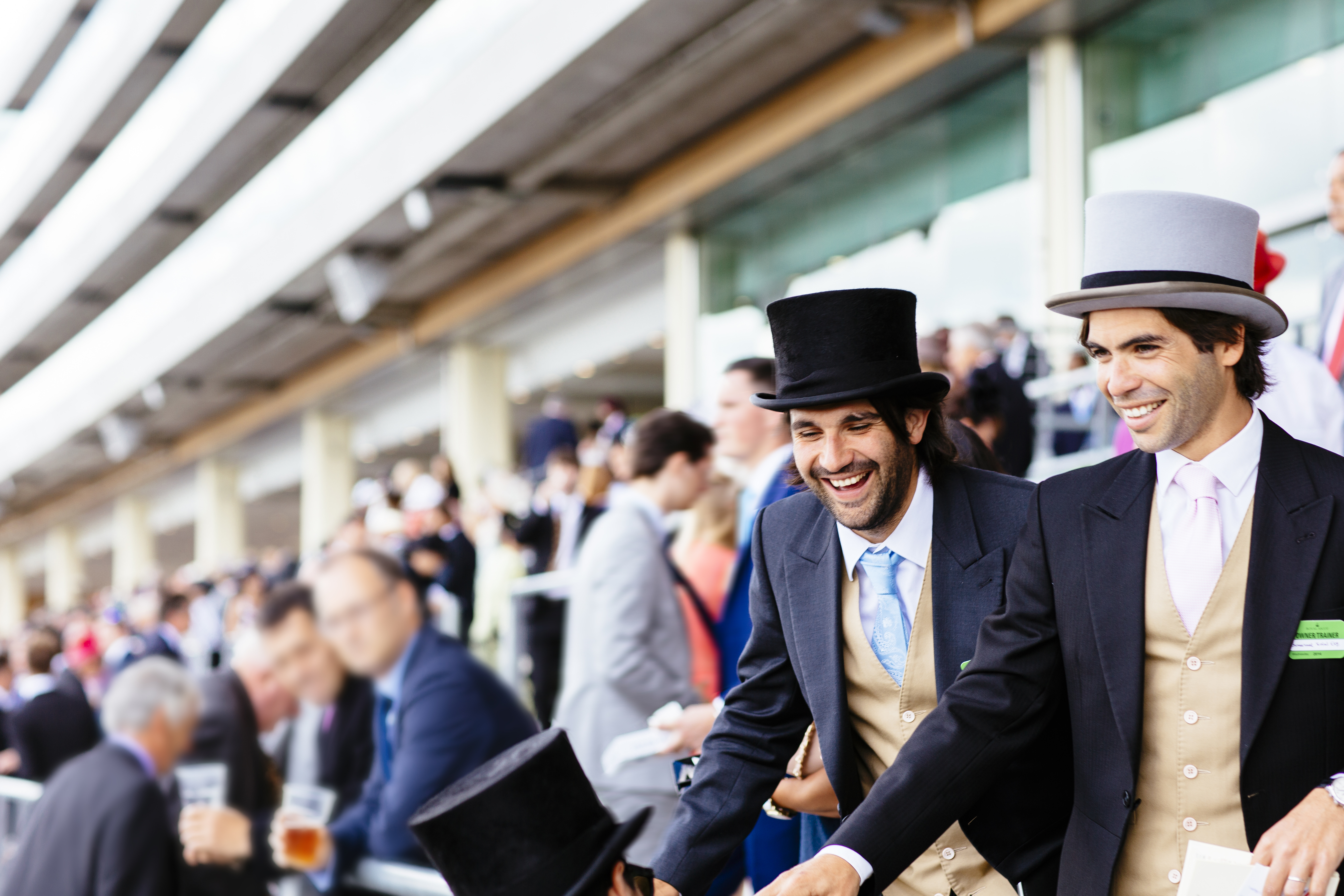 Des hommes élégamment vêtus et coiffés de chapeaux haut-de-forme dans une tribune en train de rire