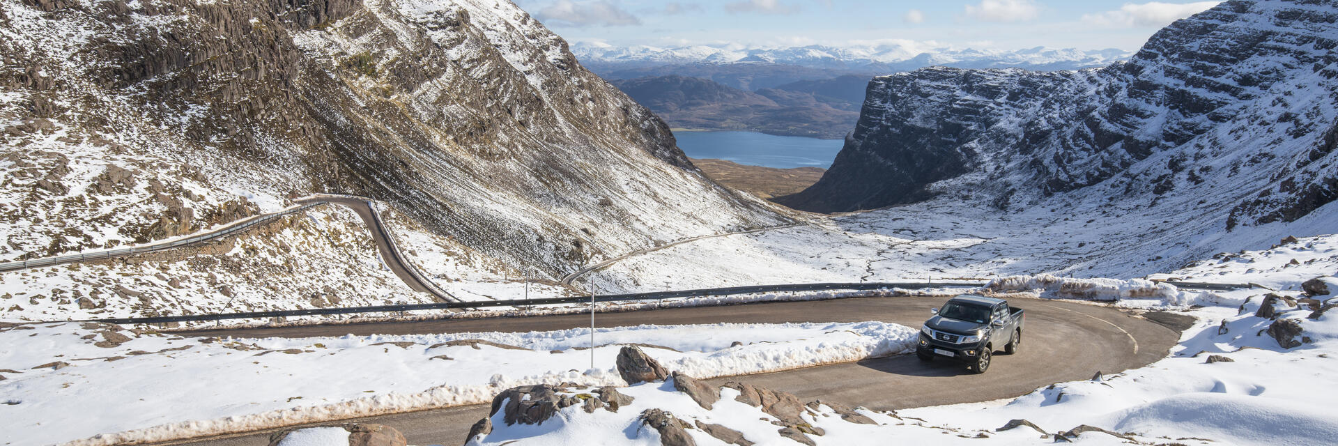 Un'auto su una strada di montagna circondata dalla neve